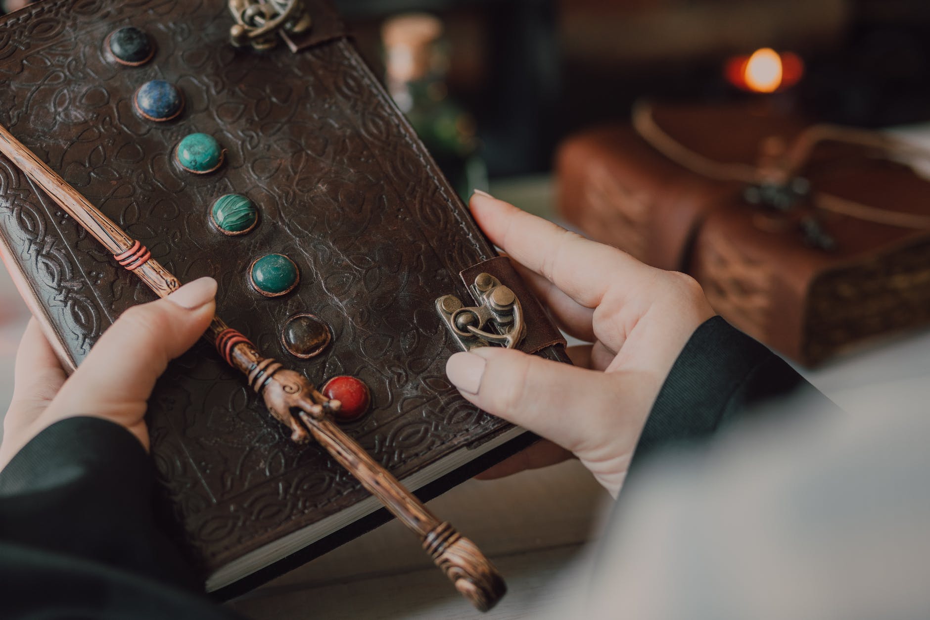 a person holding brown book and brown wooden stick